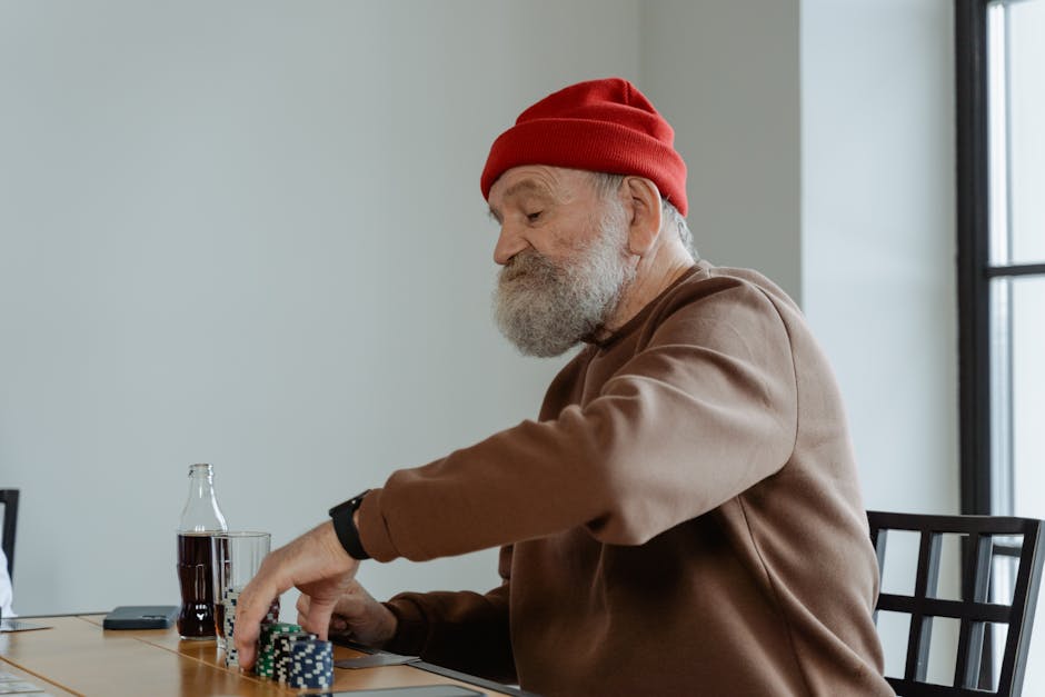Senior man with beard playing poker at home, focused and relaxed.