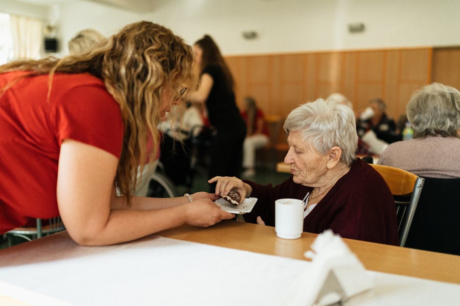 An elderly woman being assisted by a caregiver in a nursing home setting.