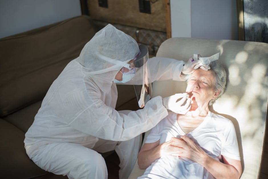 A healthcare professional in protective gear performs a COVID-19 test on a senior woman at home.