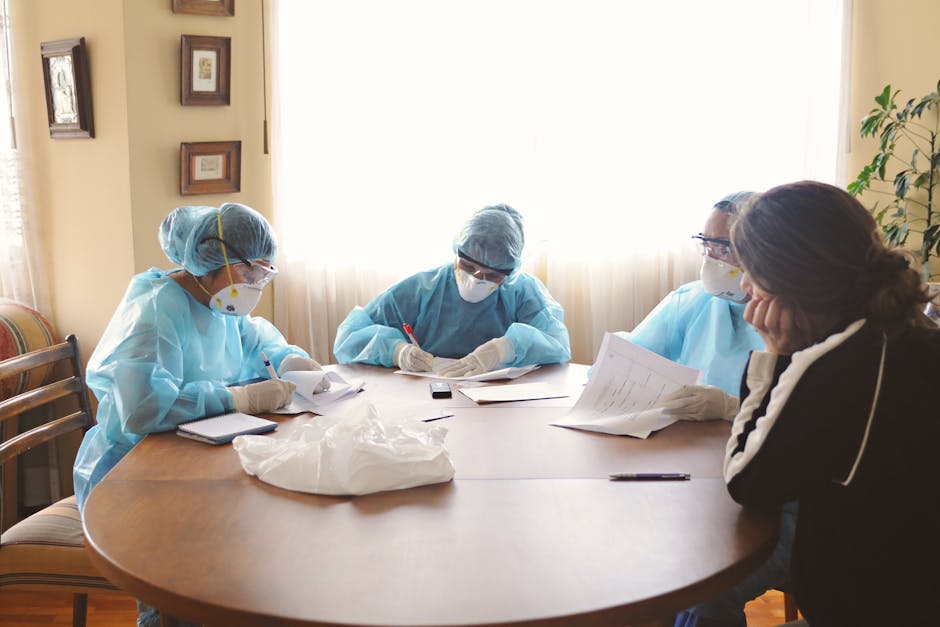 Medical team in protective equipment discussing at a table indoors.
