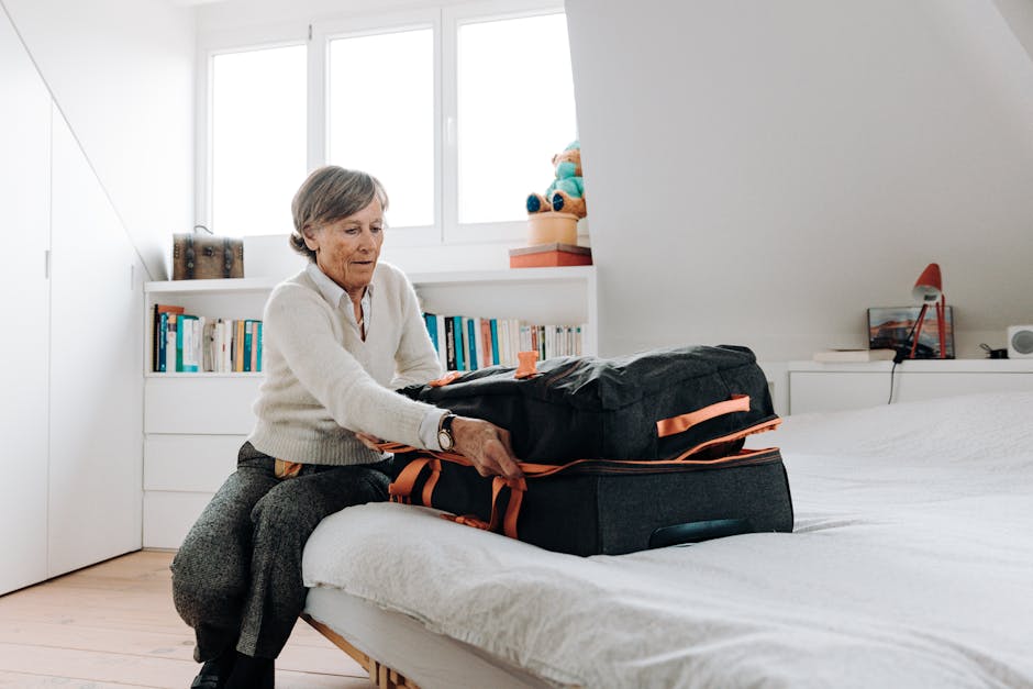 Elderly woman packing suitcase on bed in bright, modern bedroom setting.